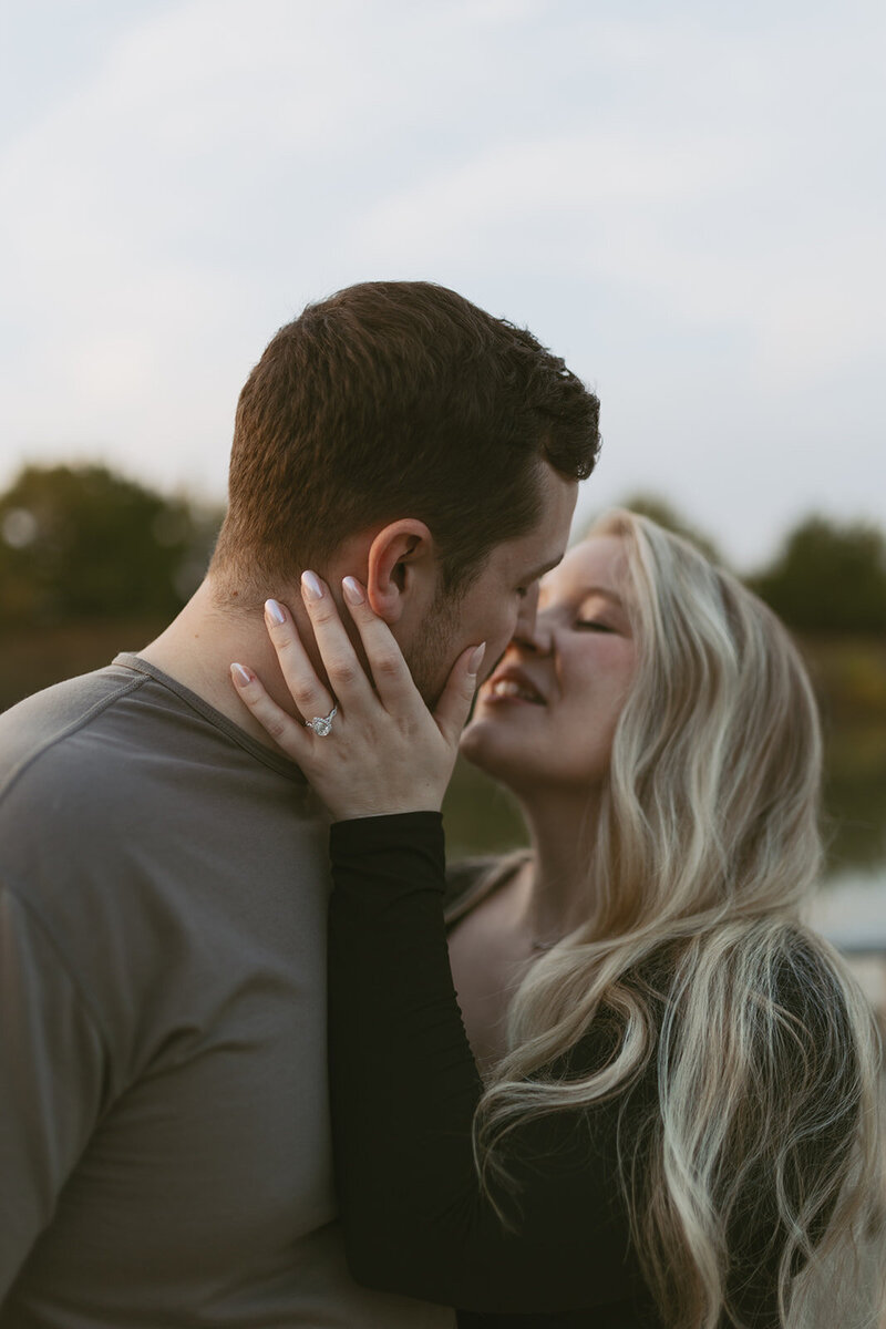 A couple about to kiss during their sunset portraits at Great Plains Nature Center in Wichita, KS, capturing a tender and romantic moment as the golden light of the setting sun surrounds them.