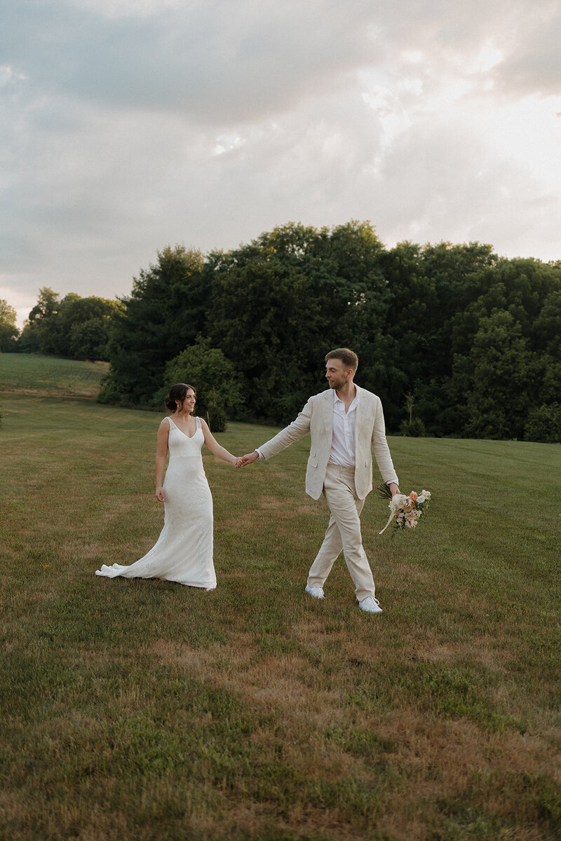 bride and groom walking together in grass