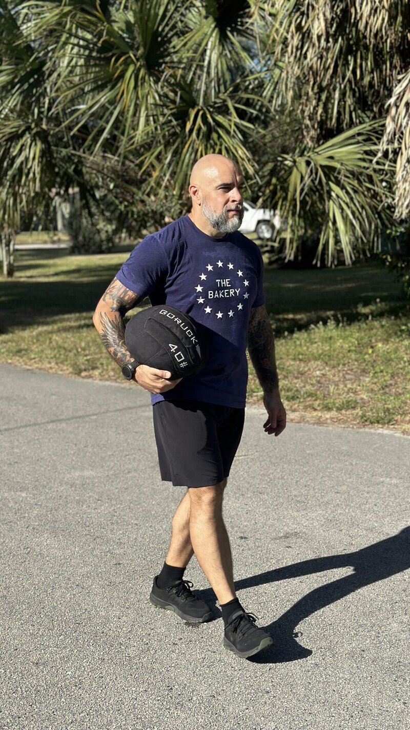 Athlete of The Bakery performing GORUCK sand medball workout for endurance and strength training.