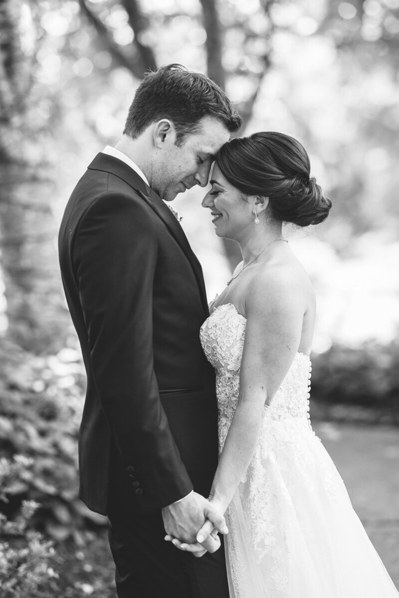 bride and groom holding hands and snuggling in black and white