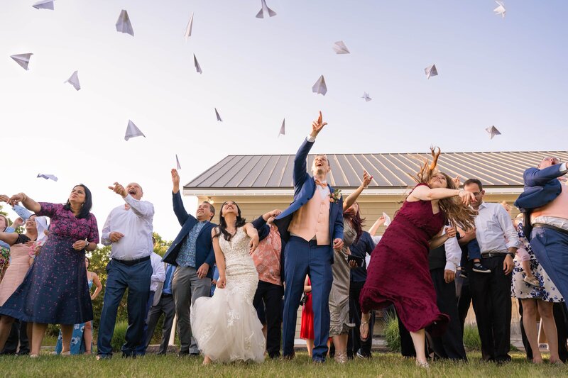 Bride and groom hold paper airplane contest with their guests.