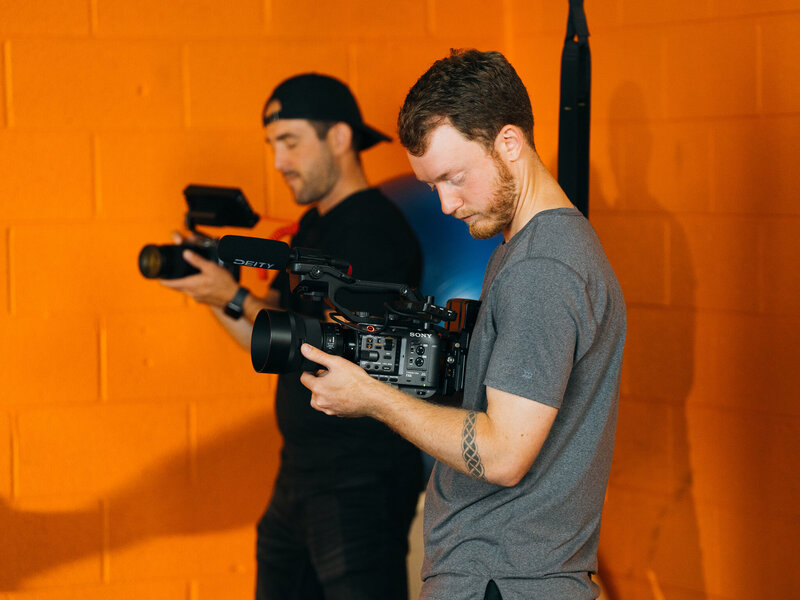 A videographer adjusting a camera rig on set, carefully preparing to capture high-quality footage. This image highlights the professionalism and technical expertise involved in video content creation at Future Fox Media, Denver, Colorado.