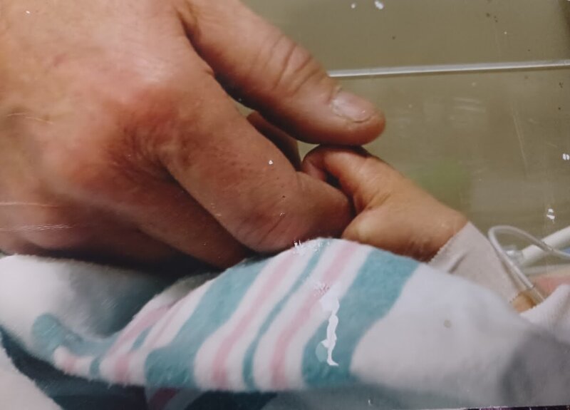Close-up of mother holding baby's hand, symbolizing reconnection and healing after birth trauma