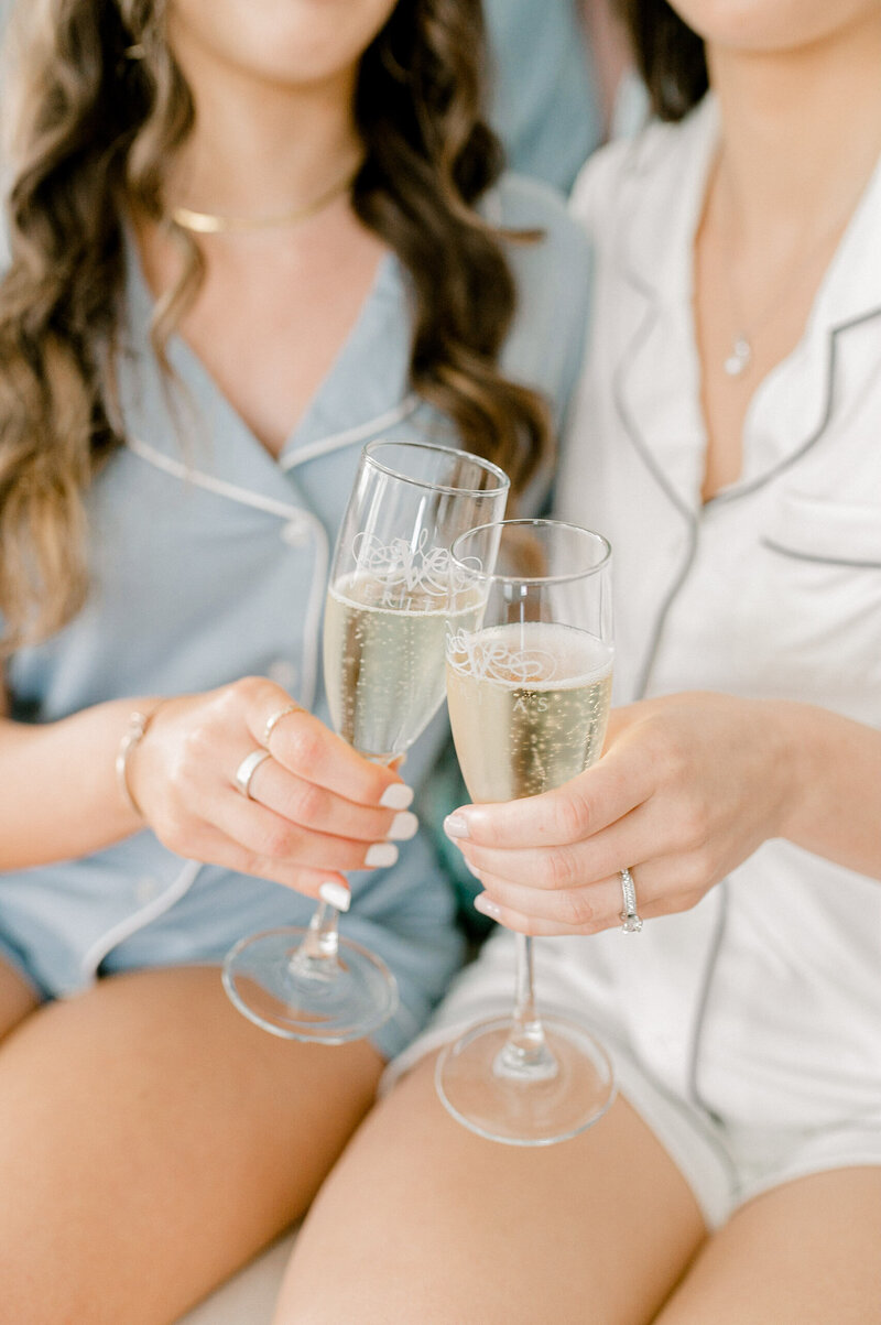 a bride clinking a glass of champagne with a bridesmaid