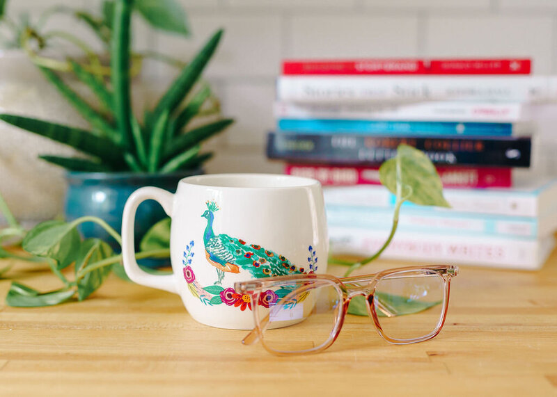 Brand imagery of a coffee mug, glasses, and copywriting books and resources.