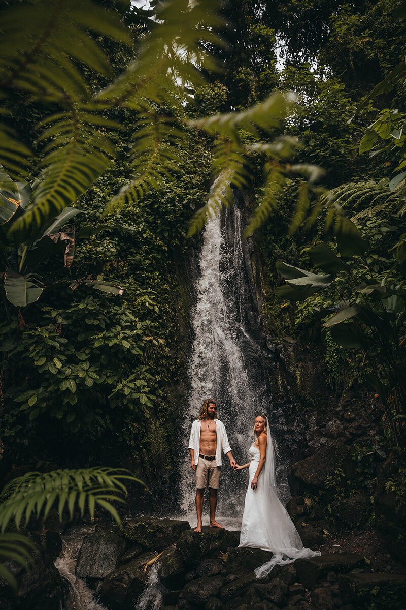 couple hold hands at waterfall
