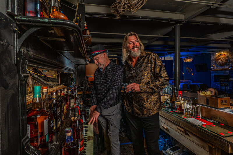 two band members behind a bar playing a piano