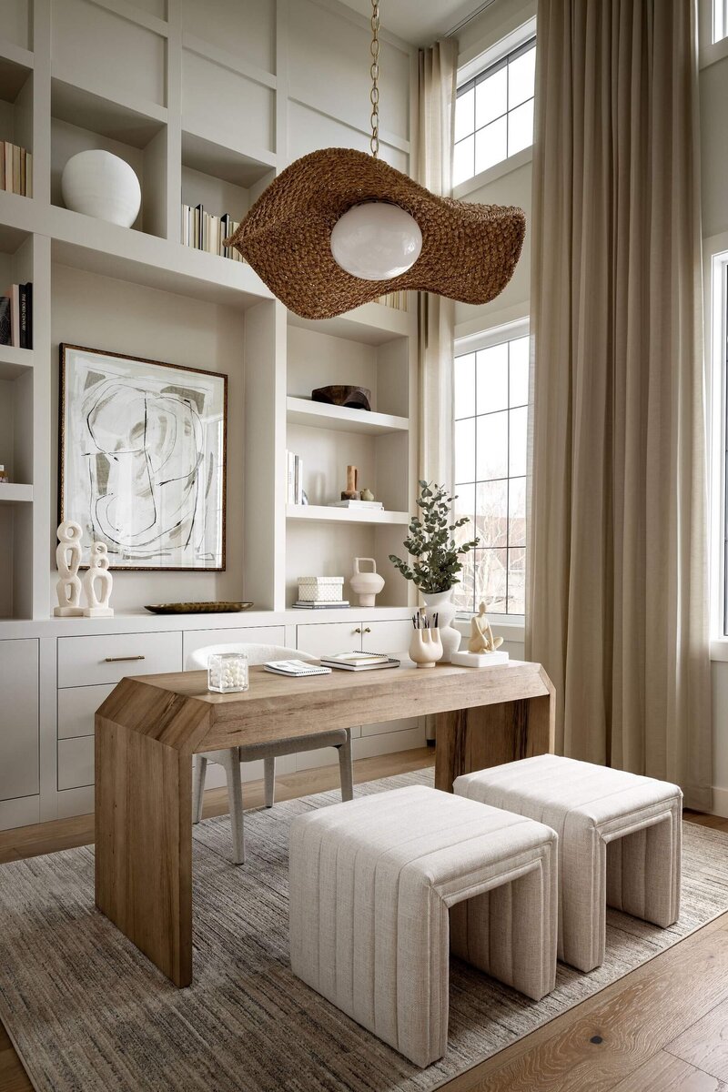 Creative art and reading space with tall ceilings, rattan light fixture, wood accents and neutral artwork and accessories.