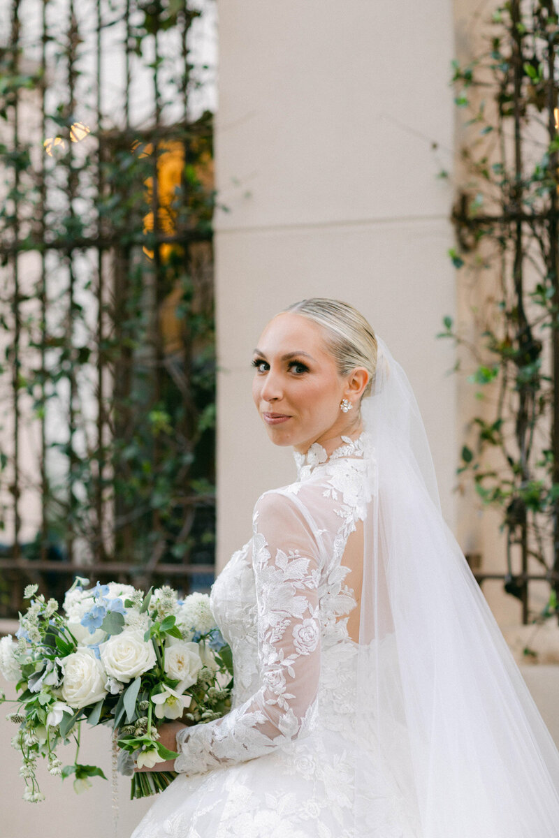 Kelly, a bride, standing and holding bouquet at the NOPSI hotel in New Orleans