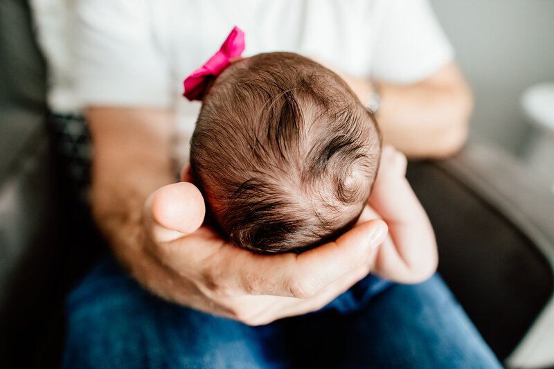 up close of dad's hands holding baby girls head