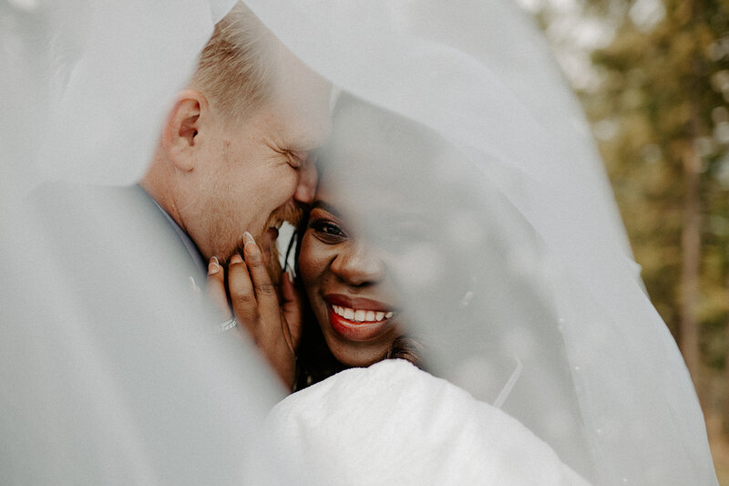 Bride and groom share an intimate moment under the veil.