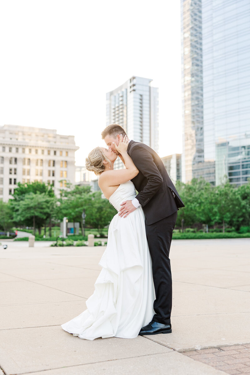 bride and groom kissing with a city buildings in the background