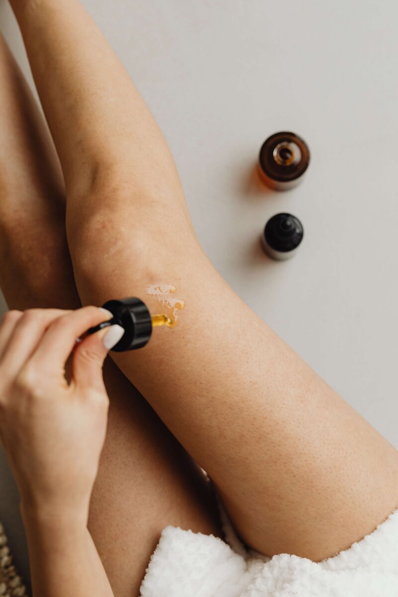 A woman applying serum and skincare products to her legs