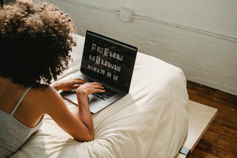 Woman lays on a bed culling through photographs.
