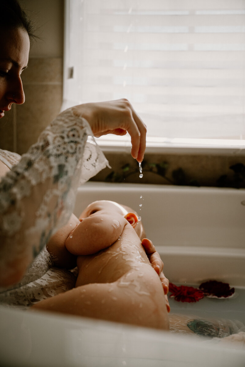 Mom and baby in milk bath for motherhood photo with mom dripping water on baby in Studio in Severn Maryland photographed by Bethany Simms Photography