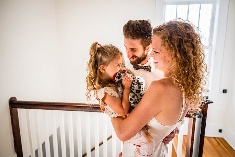 A couple on their Roanoke wedding day take a moment to pause during getting ready to play with their daughter on their elopement day.