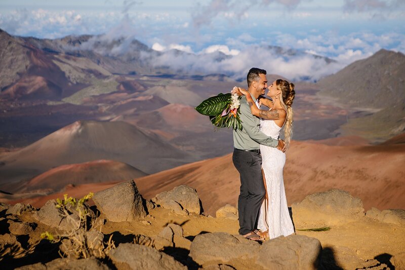 A man and woman embrace on the cliffside overlooking Haleakala National Park