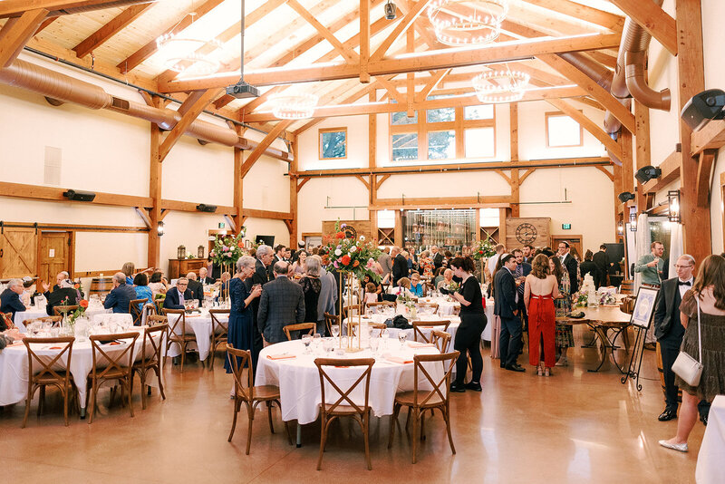 guests gather inside the barn for wedding reception at the barnwood events in madison, winconsin.