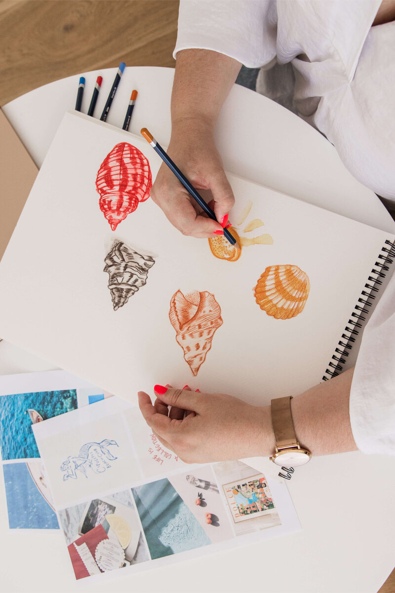 Leith drawing seashells with moodboard images, pencils and laptop