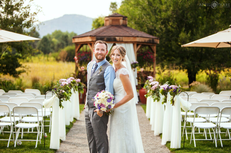 Couple pose in front of their ceremony space of the Open Air Chapel at Chatfield Farms wedding day