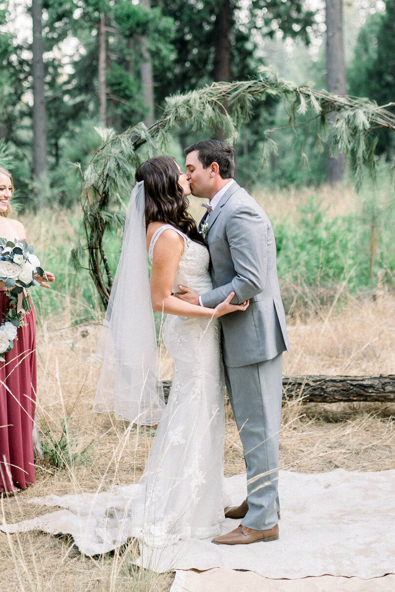 Tiffany Longeway Photography captures a heartfelt exchange between a bride and groom during their intimate forest wedding ceremony in Santa Barbara. This picturesque moment, framed by natural woodland and a bespoke floral arch, exemplifies the unique blend of romance and rustic elegance Santa Barbara offers to couples seeking a luxury wedding experience in a natural setting.