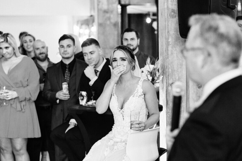 Emotional bride covers her mouth during the father of the bride speech