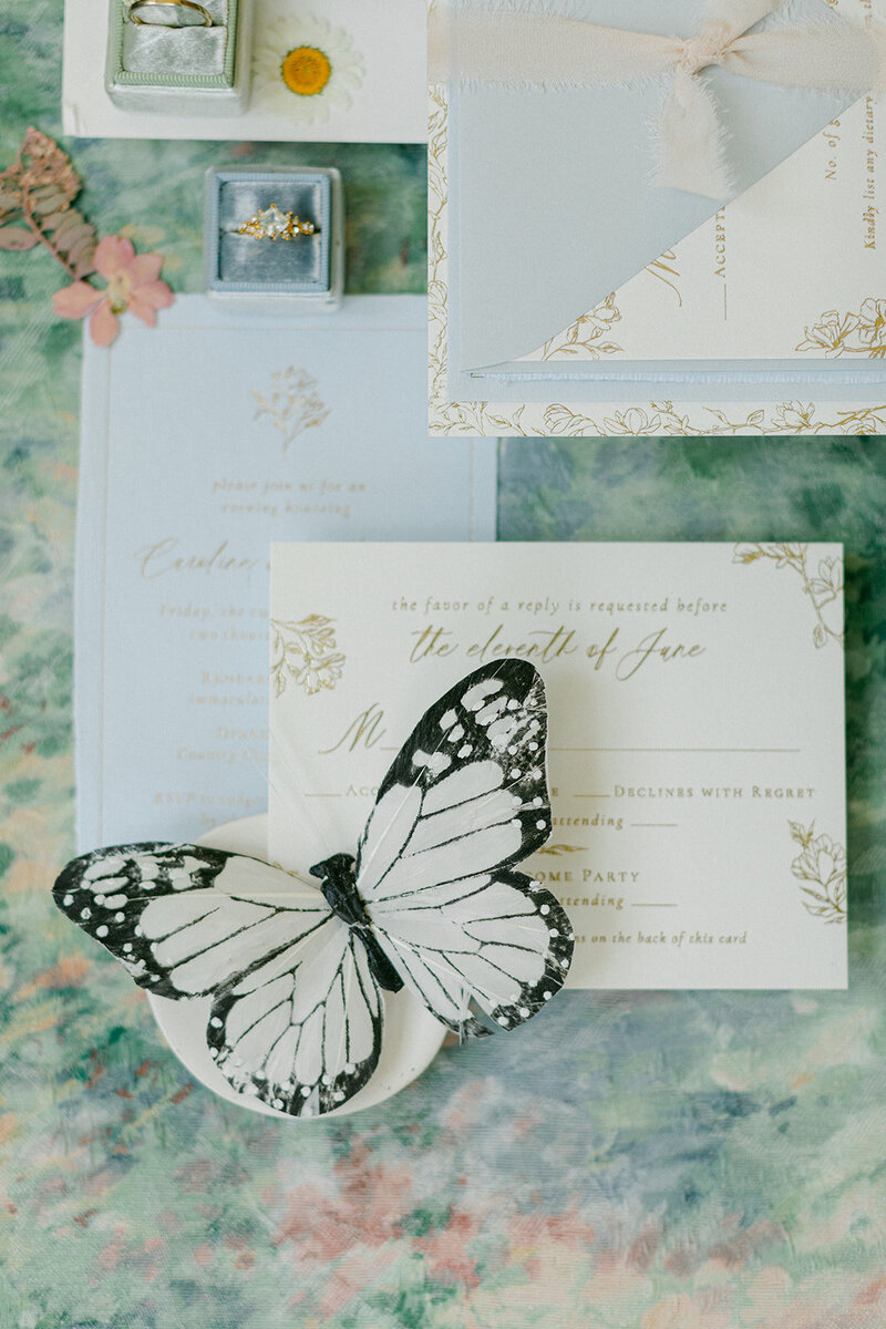 Soft blue linen flat lay mat styled with romantic paper goods and silk ribbon