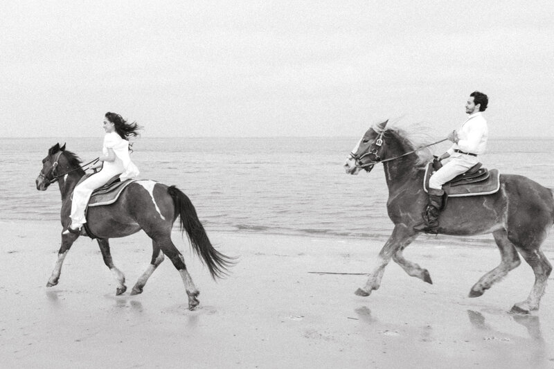 Bride and groom riding horses on a sandy beach