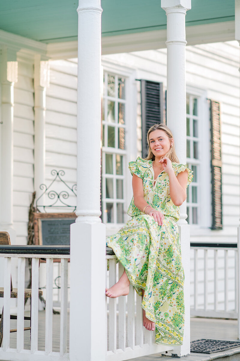 a girl posing on the banister of a front porch