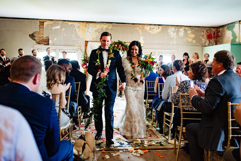 A wedding couple and their dog walking down the aisle after the ceremony at the Ford mansion in Toledo Ohio