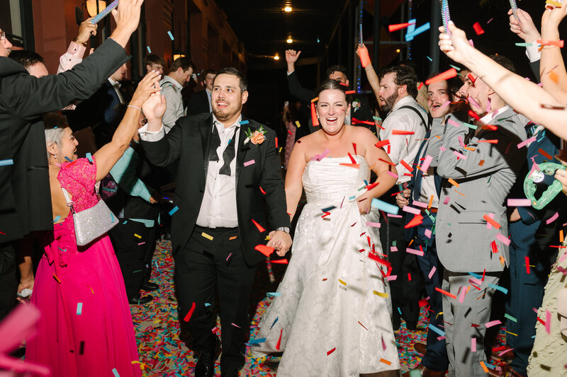 Groom dipping and kissing bride in between guests at wedding exit