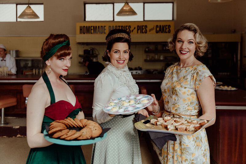 50s themed wedding reception servers holding trays of appetizers in a 50s diner.