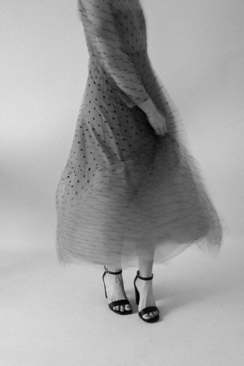 blurred black and white photo of a woman spinning in a polka dot tulle dress