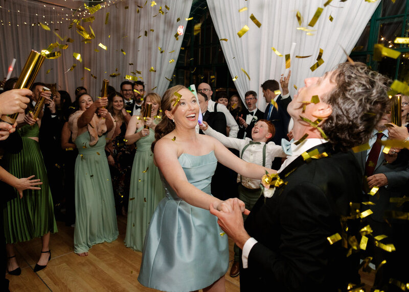 November wedding at Graylyn Estate, designed and planned by Charming Carolina — bride and groom dancing in the center of the dance floor as guests pop confetti cannons over them during the reception.