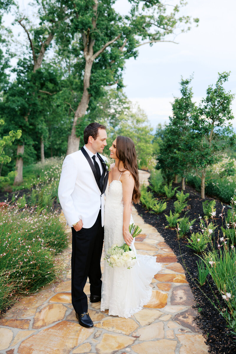 Bride and groom kiss on a wildflower-lined stone path with mountain views at Nichols Heir, a modern outdoor wedding venue in Tennessee