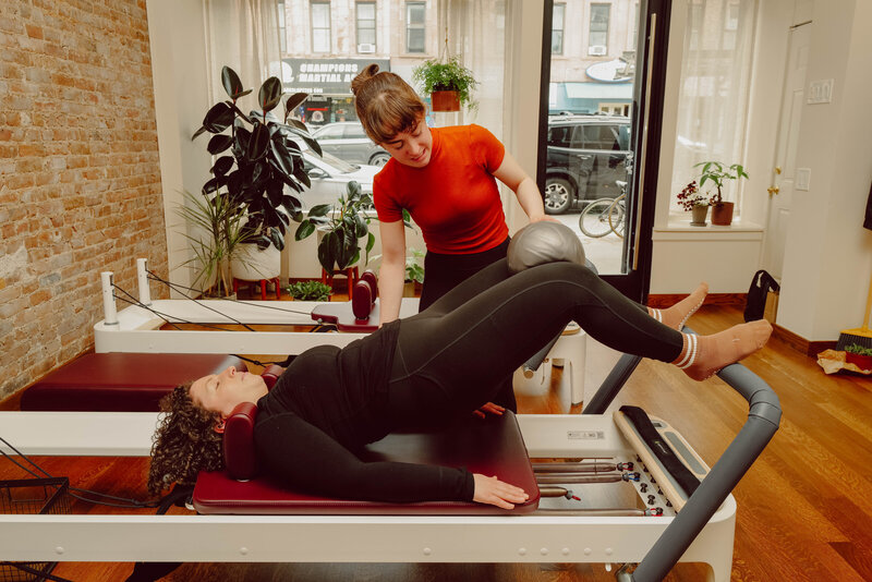 A one-on-one Pilates private session where an instructor is providing guidance to her client
