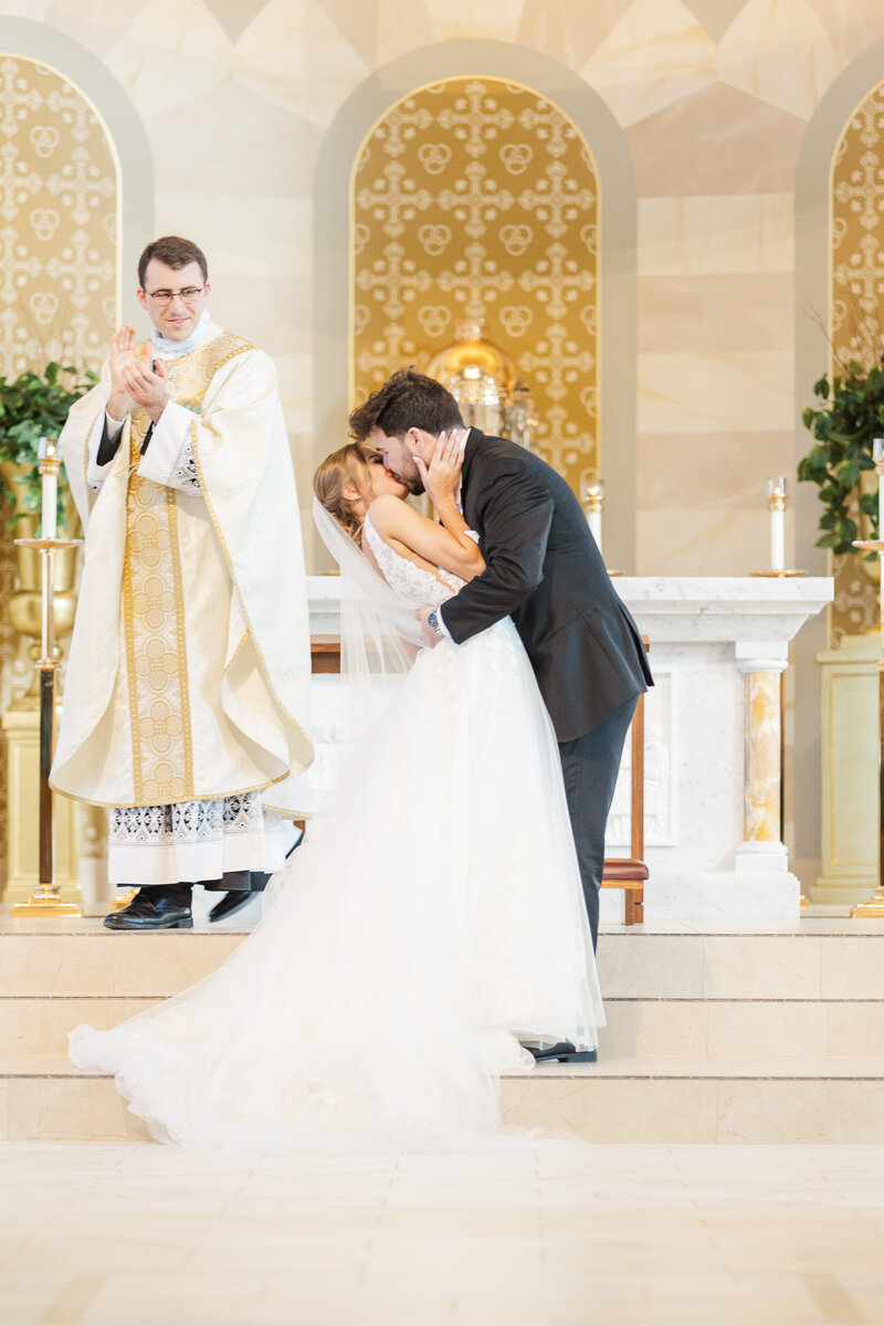 bride and groom kissing in a Catholic church during their wedding ceremony