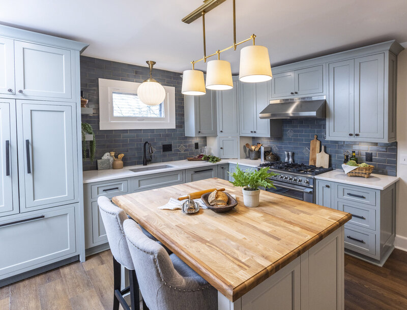Beautifully decorated kitchen with grey cabinets and a butcher block island.