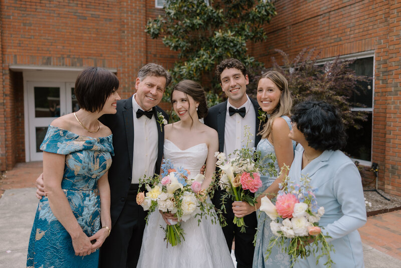 Bride and bridesmaids walk through a field laughing at one another