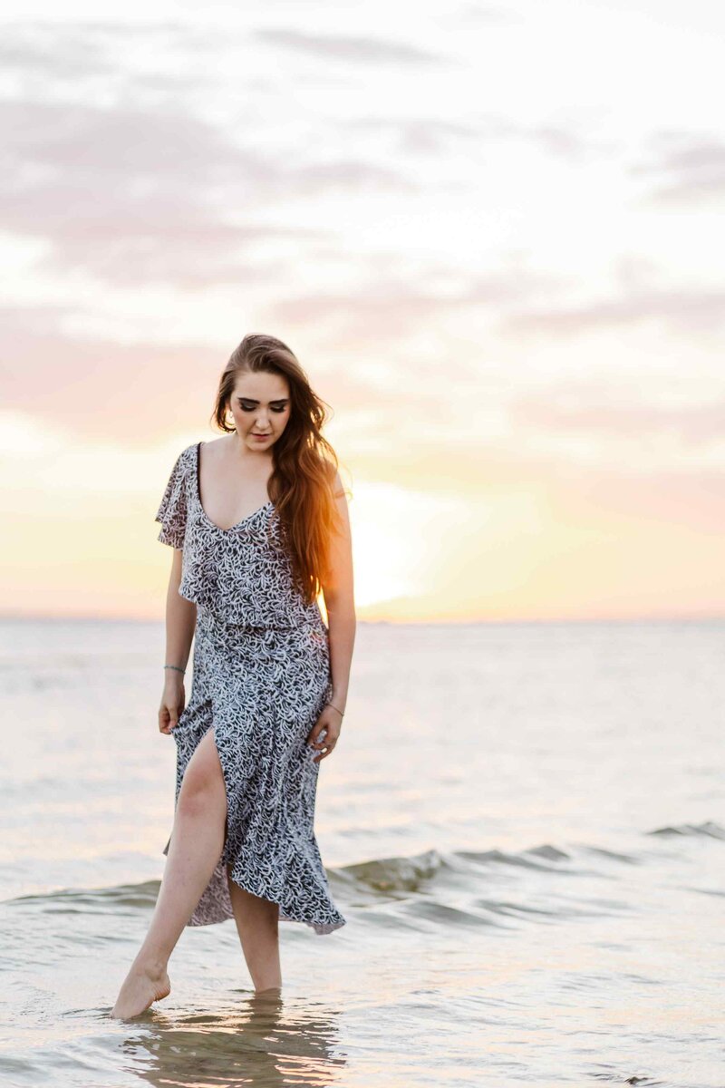 Woman looking down, tiptoeing through the ocean shoreline
