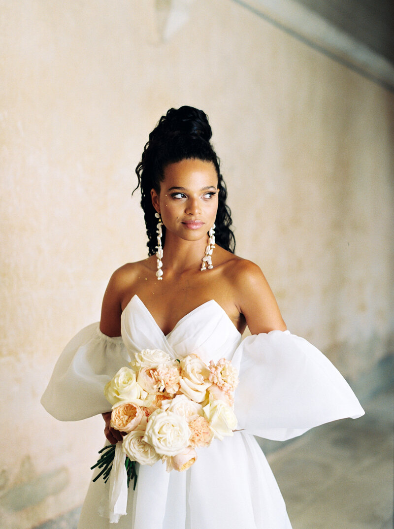 Beautiful bride in strapless gown holds bouquet and looks into the distance