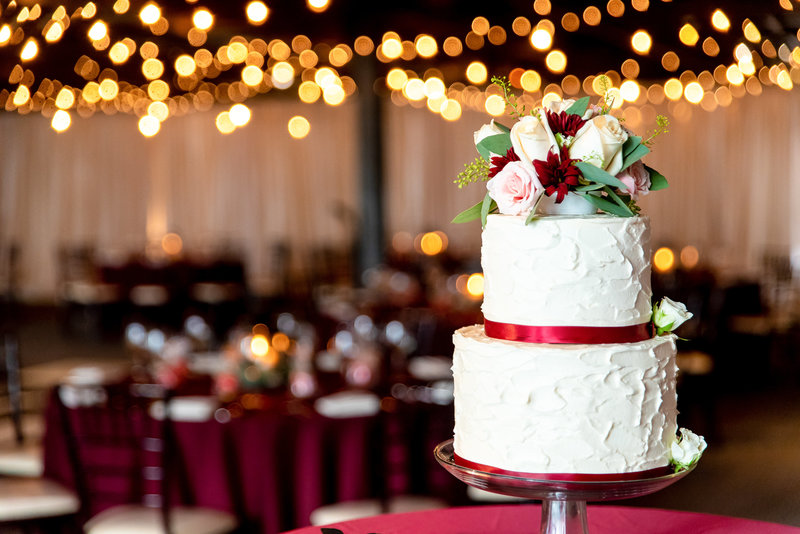 2 tiered reception cake with red ribbons and light bokeh behind