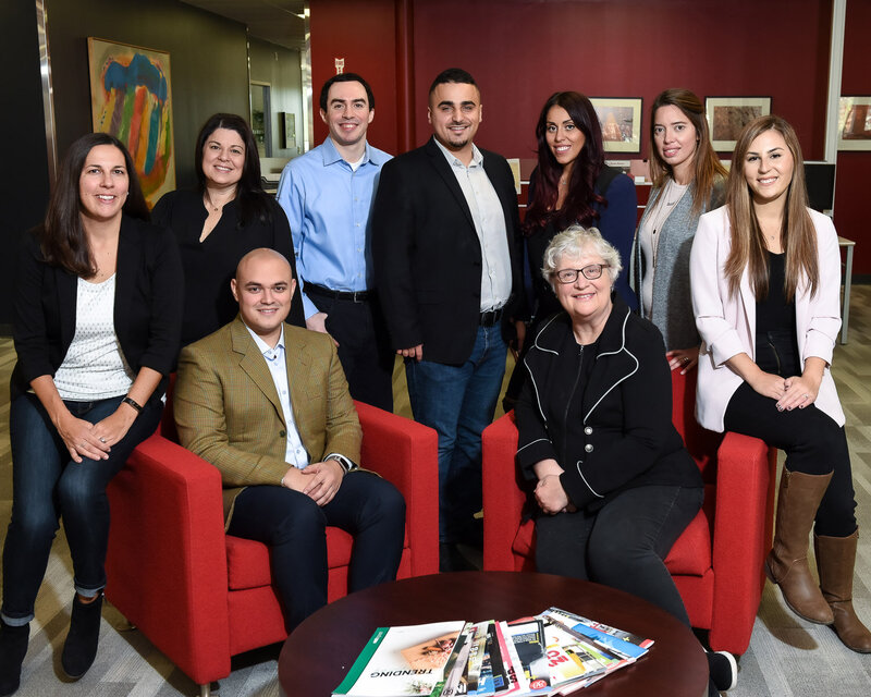 Corporate group photo of Toronto leadership team standing and sitting confidently in their  office building