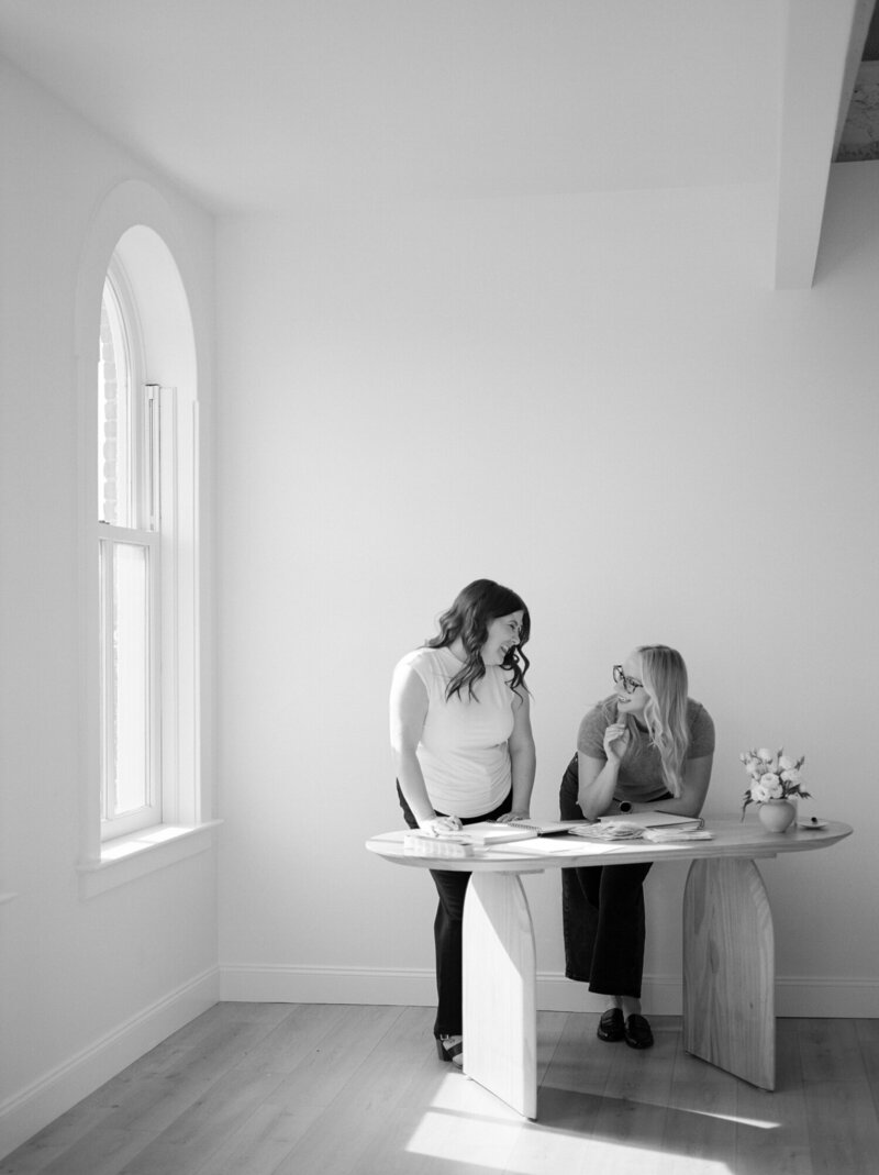 two women collaborate on a brand project at desk in light-filled natural studio with papers, inspiration