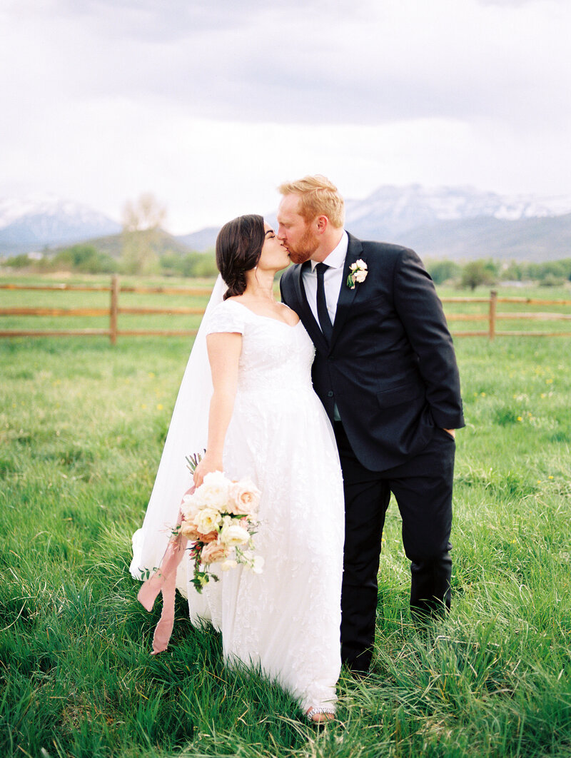 Bride and Groom walking and kissing in field