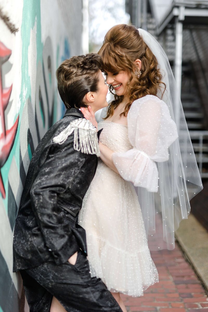 LGBTQ+ styled shoot with bride and bride kissing in alley