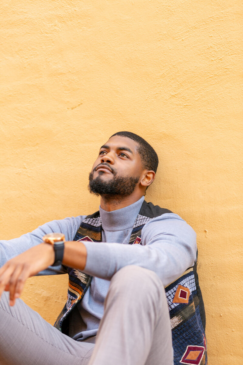 Man seated with head leaning back against yellow wall