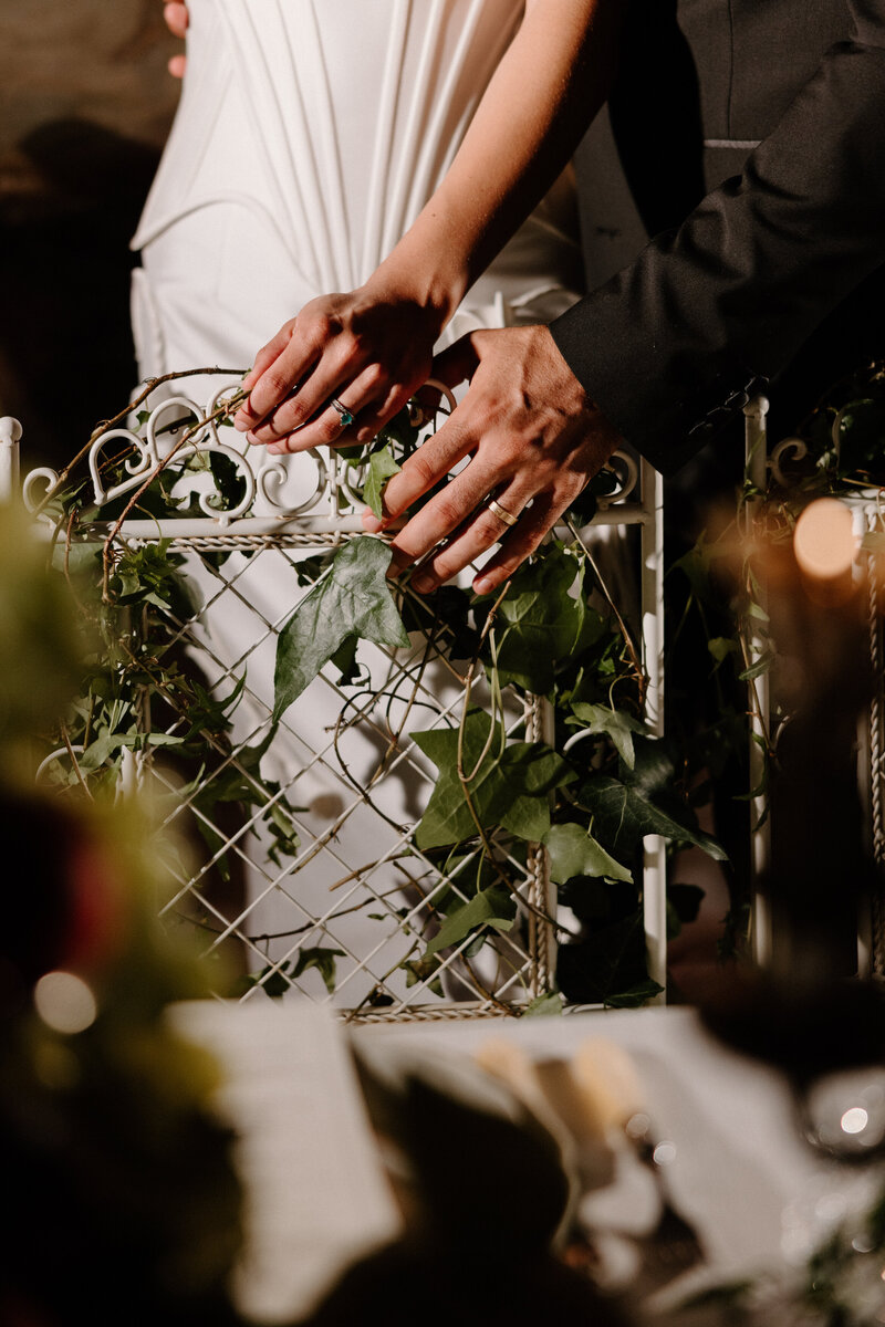 A close up of two hands on a chair showing off wedding rings 