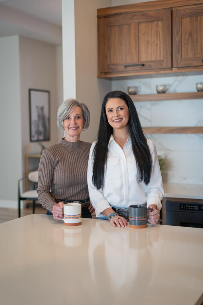 mother and daughter holding coffee mugs in kitchen