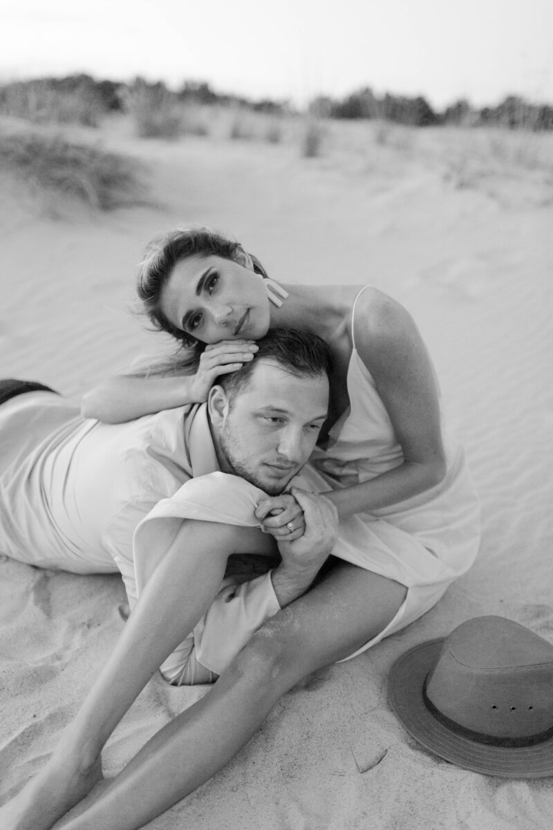 Couple sitting on beach, man lying in girlfriend's arms.